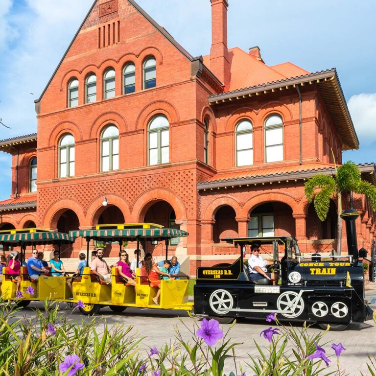 Conch Tour train filled with guests taking a tour in front of the Key West Custom House